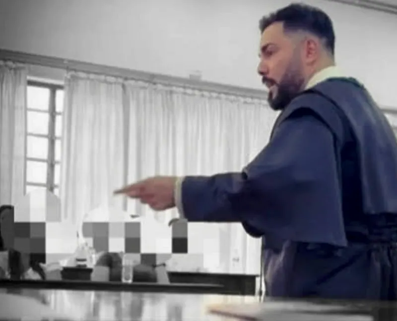 O advogado de toga em pé, apontando, falando no plenário, em preto e branco, com os rostos das outras pessoas borrados